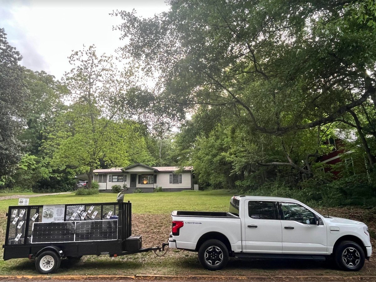 Rabbit Hole Landscaping's all-electric Ford F-150 Lightning towing a trailer of solar panels on an Athens, GA job site